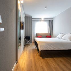 Vista de interior de dormitorio con cama doble, televisor y sofá en eñ Hot el Ibis de Valencia