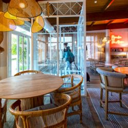 Interior del bar cafetería con mesas de madera  y mimbre del hotel Ibis de Valencia