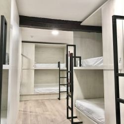 Dormitorio con literas y camas blancas en el Hostel Quartier León