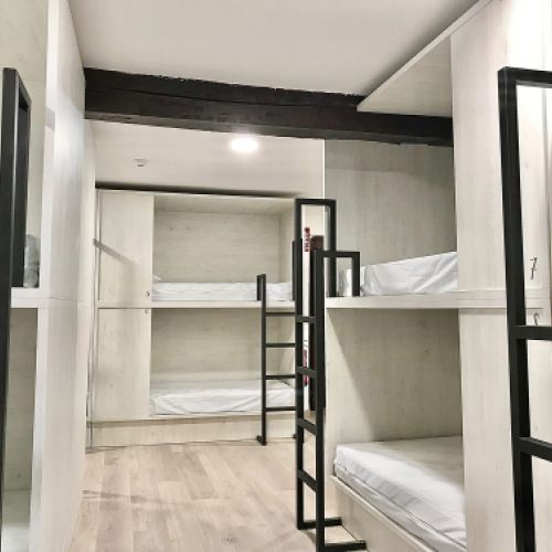 Dormitorio con literas y camas blancas en el Hostel Quartier León