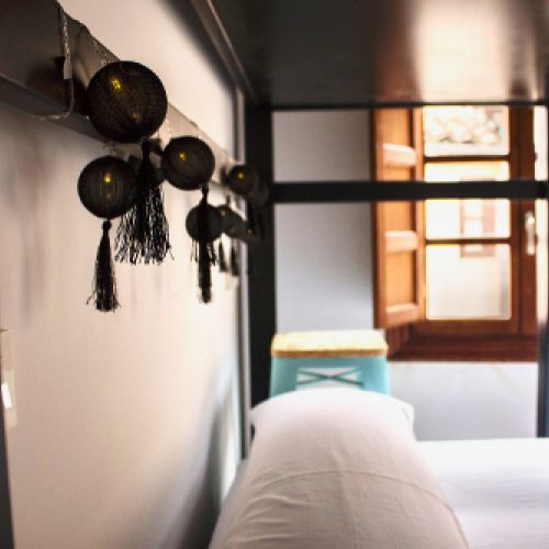 Detalle de camas literas con decoración de guirnaldas con luces en el Hostel Palacio de Jabalquinto en León